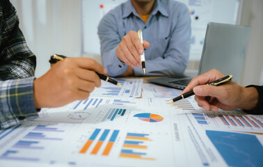 A professional business team collaborates around a conference table, analyzing charts, discussing...