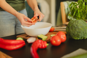 Woman cutting fresh vegetables in the kitchen. Healthy cooking, food preparation and lifestyle concept
