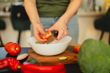 Woman cutting fresh vegetables in the kitchen. Healthy cooking, food preparation and lifestyle concept
