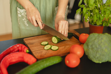 Woman cutting fresh vegetables in the kitchen. Healthy cooking, food preparation and lifestyle concept
