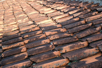 Side view of mossy clay tile roof. Textured background of old tile roof. Abstract detailed backgrounds. Roof of house covered in moss and cracks due to weather. Negative space