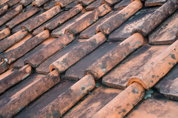 Side view of mossy clay tile roof. Textured background of old tile roof. Abstract detailed backgrounds. Roof of house covered in moss and cracks due to weather. Negative space