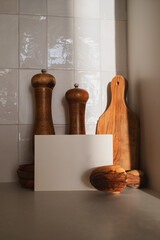 Wooden olive kitchen utensils with paper blank for menu and recipe. Modern culinary mockup for cooking healthy food.
