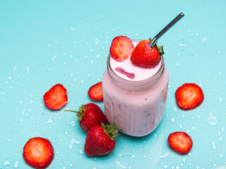 A mason jar brimming with a cool strawberry drink, garnished with fresh strawberries and metal straw
