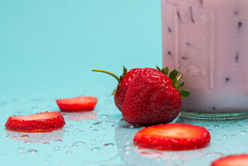 A mason jar brimming with a cool strawberry drink, garnished with fresh strawberries and metal straw