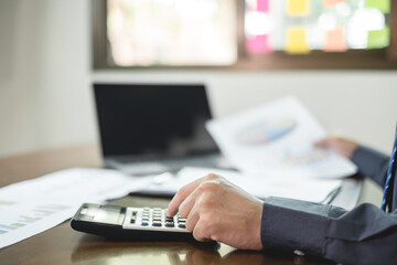 The businessman hand sits at their desks and calculates financial graphs showing the results of...