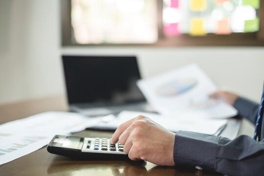 The businessman hand sits at their desks and calculates financial graphs showing the results of their investments planning the process of successful business growth - Powered by Adobe