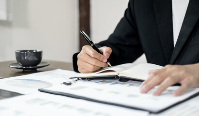 Asian businessman sit at their desks and calculate financial graphs showing results about their...