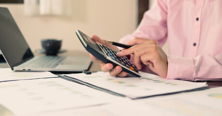 Asian businessman sit at their desks and calculate financial graphs showing results about their...