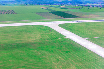 Airfield with intersecting concrete runways surrounded by green fields. Visible from above, the...
