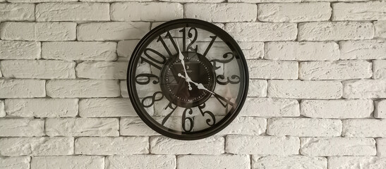 clock on the wall, black clock on a white brick wall, mechanical round clock with hands, time