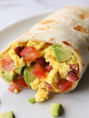 Delicious breakfast burrito with scrambled eggs, bacon, tomato, and avocado
