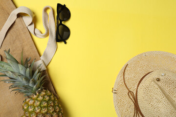 Tropical vibes shot from above. Straw hat, sunglasses, pineapple, wicker bag, beach accessories on...