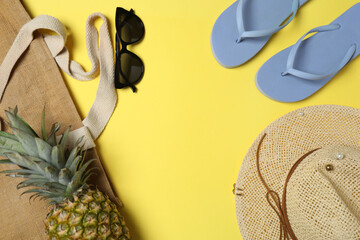 Tropical vibes shot from above. Straw hat, sunglasses, pineapple, wicker bag, beach accessories on...