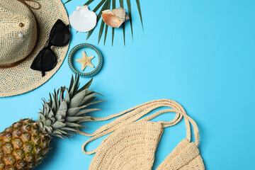 Tropical vibes shot from above. Straw hat, sunglasses, pineapple, wicker bag, beach accessories on...