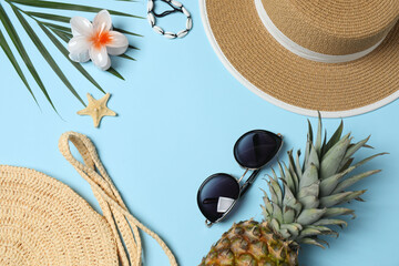 Tropical vibes shot from above. Straw hat, sunglasses, pineapple, wicker bag, beach accessories on...