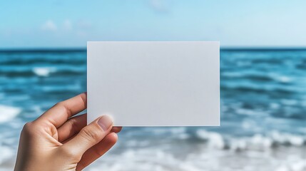 Hand Holding White blank Card Against Beach Backdrop Minimalist Design with Ocean View