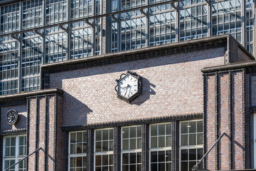A large wall clock mounted on the exterior of Berlin Friedrichstrase station. Historic architecture with detailed brick and ironwork.