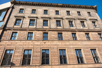 The historic building facade shows clear signs of war damage with visible bullet holes. The window structure and patina give the building character.