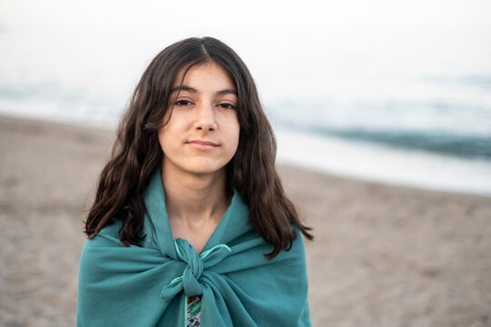 12-year-old teenage girl on the beach with her towel looking at the camera