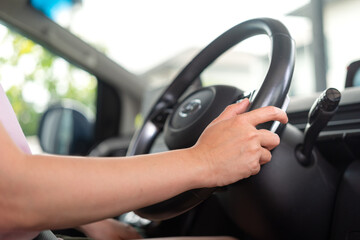 A car driver is holding and controlling on steering wheel of the modern car with digital display as...