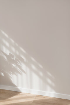 Aesthetic soft sunlight shadows pattern on neutral beige plaster wall and wooden floor background, minimal elegant home design interior detail, backdrop with empty copy space