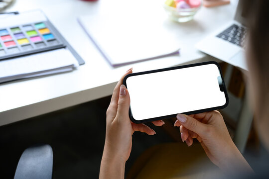 Female designer using a smartphone at creative workplace