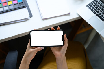 Woman using a smartphone in landscape mode in creative studio