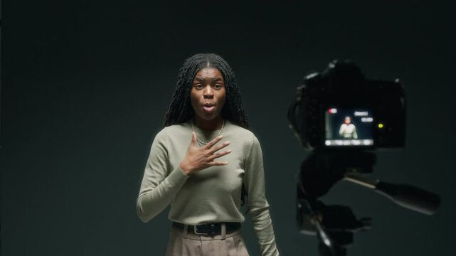 African American actress reading off script while performing passionate monologue on camera against black background in studio