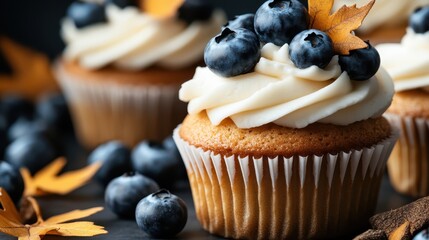 A close-up of frosted cupcakes topped with fresh blueberries and decorative leaves, illustrating the scrumptious appeal of desserts in a charming, appetizing setting.