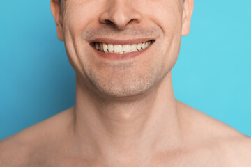 Smiling man after shaving on light blue background, closeup