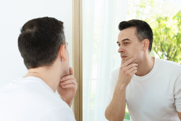 Handsome man after shaving near mirror at home