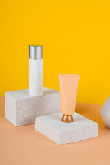 Plastic white tube for cream or lotion. Skin care or sunscreen cosmetic with stylish props on yellow background.