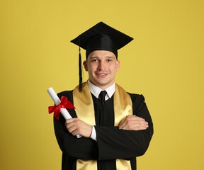 Happy student with diploma after graduation on yellow background