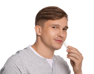 Young man applying lip balm onto his lips on white background