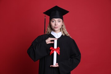 Student with diploma after graduation on red background