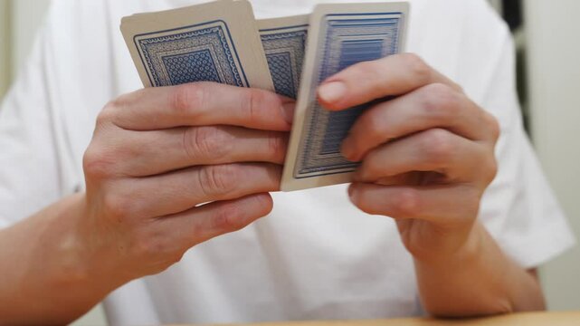 without a face. Hands of a man in a white t-shirt with cards during the game. gambling. A board game for spending leisure time with friends and family.
