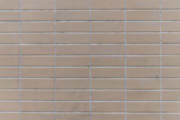 abstract background of an old wall covered with beige ceramic tiles close up