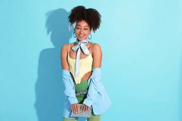 Fashionable portrait of beautiful Brazilian woman in stylish outfit on light blue background