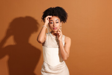 Fashionable portrait of beautiful Brazilian woman in stylish outfit on light brown background