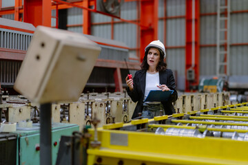 Woman engineer manager standing at steel production factory. Female inspector wears safety hard hat...