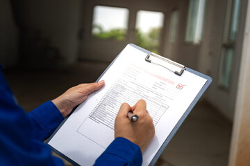 A construction foreman is checking on building quality checklist report during inspecting at the...