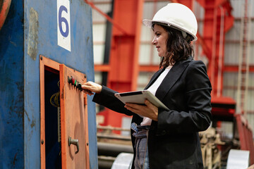 Woman engineer manager working at steel production factory. Female inspector wears safety hard hat...