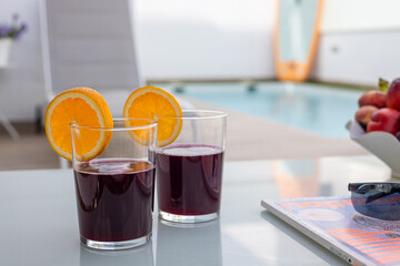 Refreshing red drinks by pool with orange slices