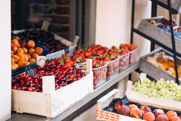 Fresh fruits and berries at outdoor market, seasonal summer treats display.