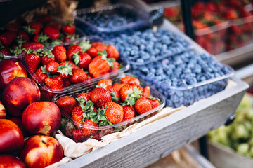 Fresh strawberries, nectarines, and blueberries at an outdoor summer market.