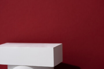 Geometric white scene on a burgundy background. A premium podium for advertising and presentation of your product. Showcase, display case.