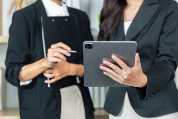 Digital Tools for Business. Two women analyzing data on a tablet in a modern office.