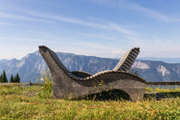 two wooden benches with modern curved design on a grassy hill with wildflowers overlooking rugged...