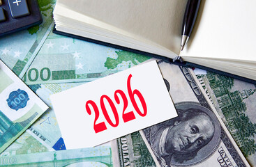 Planning financial goals for the year 2026 with currency notes and a calculator in a workspace